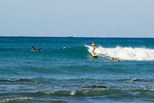 ... wave with other surfers paddling around her, Oahu Island, Hawaii, USA

